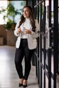 Mujer sonriente sosteniendo una taza en un entorno moderno de oficina.