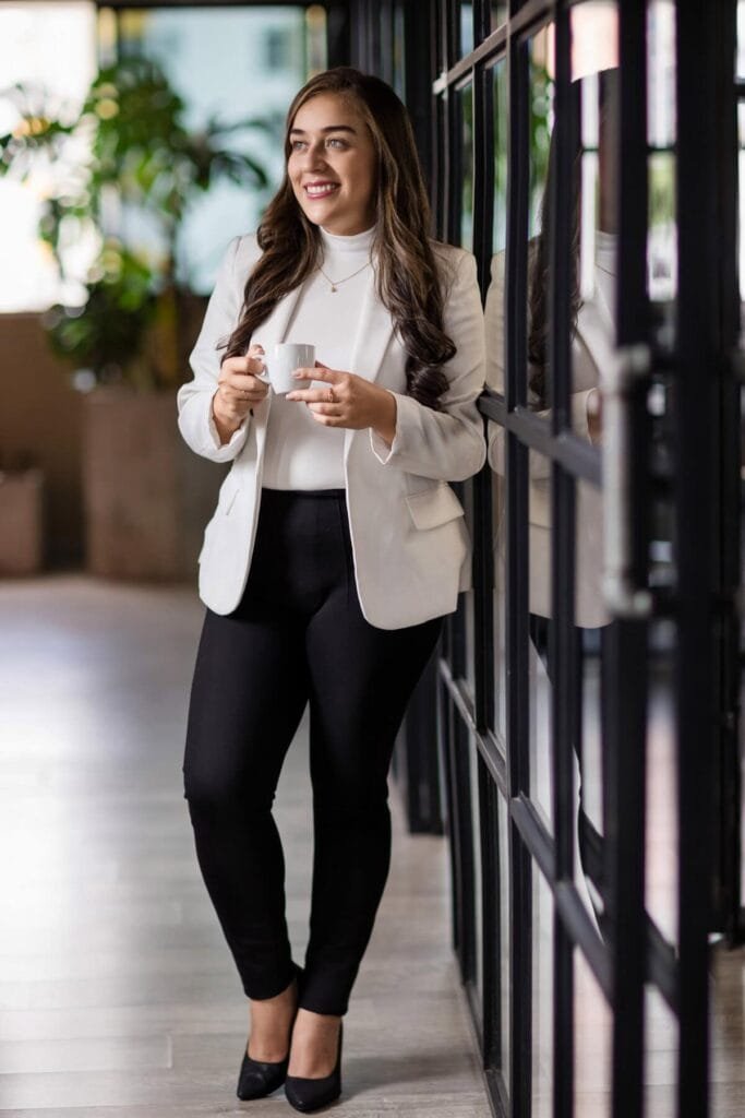 Mujer sonriente sosteniendo una taza en un entorno moderno de oficina.