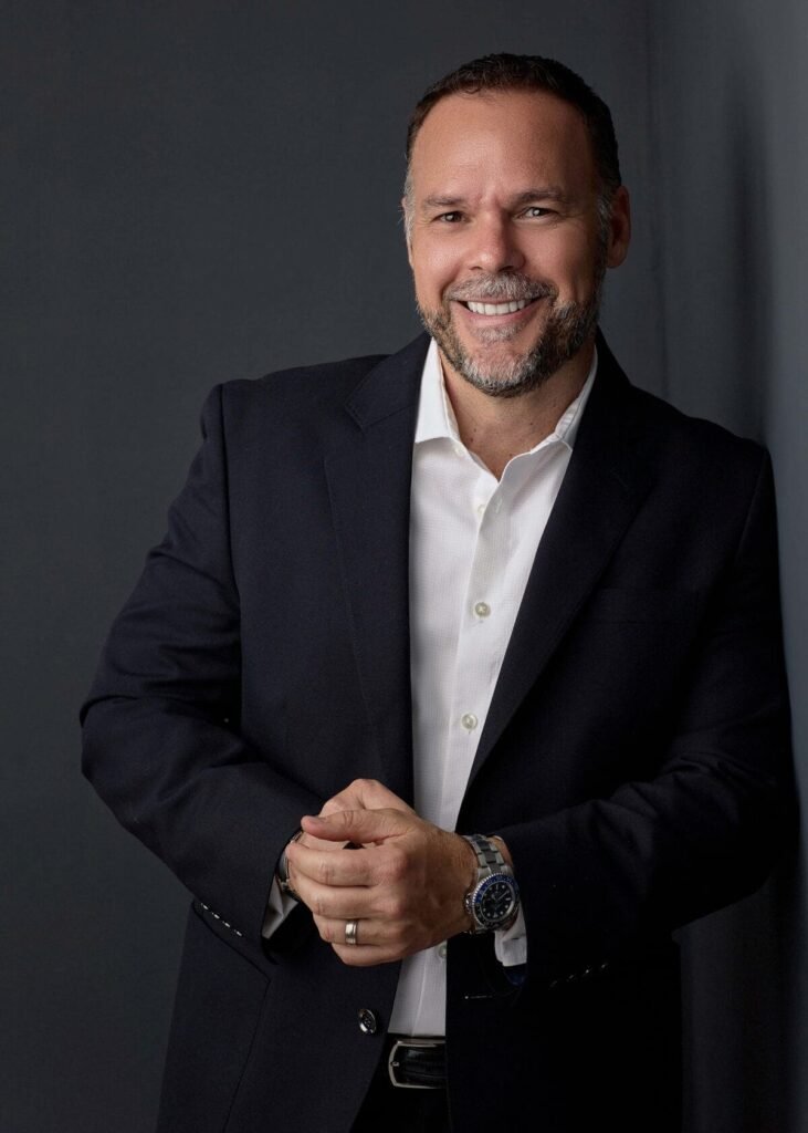 Retrato profesional con un fondo gris, mostrando una actitud amistosa.