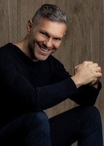 Hombre sonriendo en fondo de madera, mostrando una actitud amigable y profesional