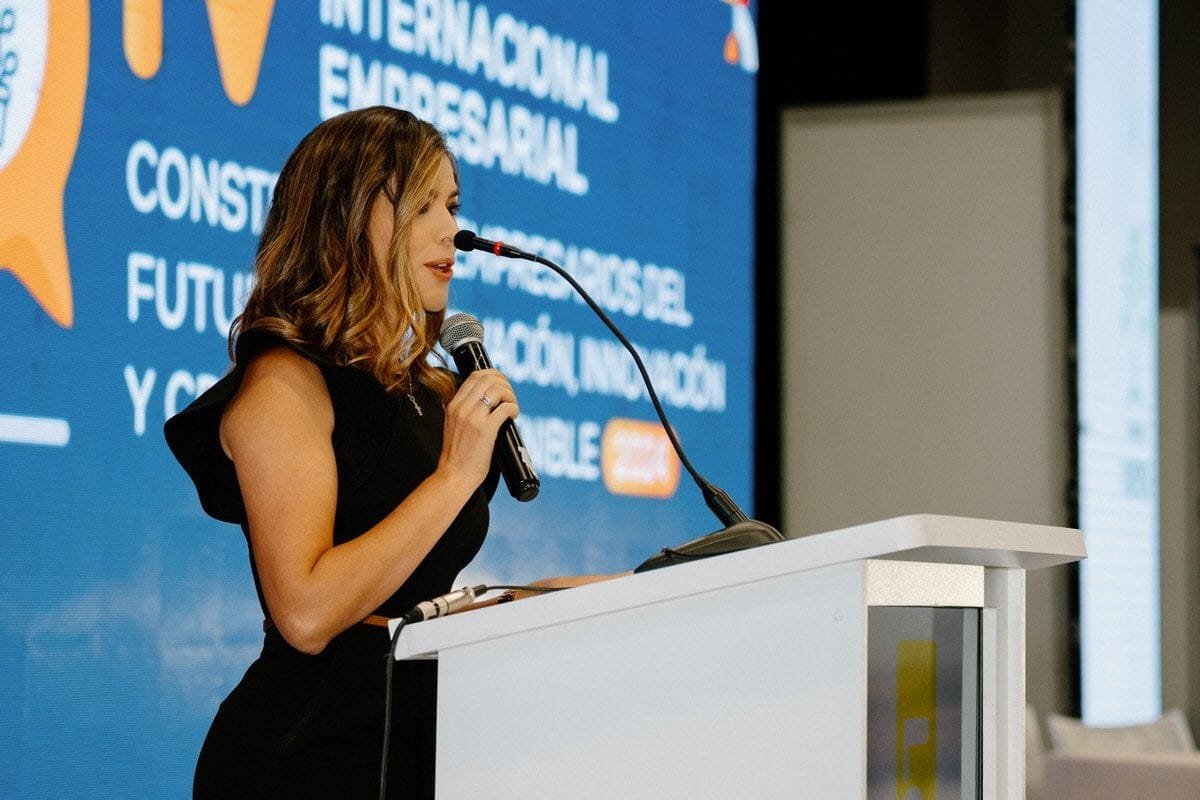 Presentadora en un evento corporativo, hablando con confianza ante el público.