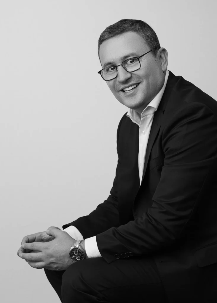 Retrato profesional de un hombre sonriente en un entorno corporativo.