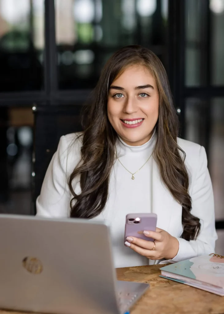 Profesional sonriente en su oficina, sosteniendo un teléfono móvil.